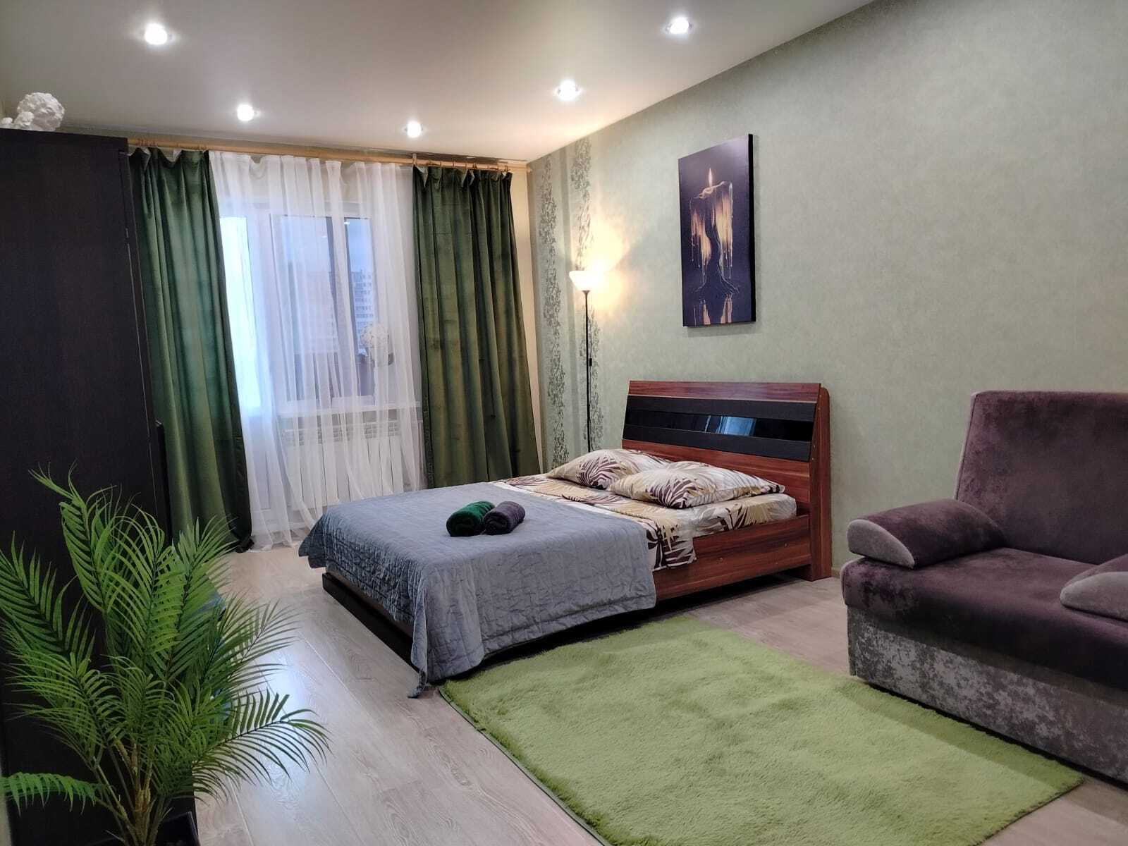 Уютная гостиная с большим окном, современным диваном-кроватью и телевизором. Идеальное место, чтобы расслабиться после насыщенного дня в Сургуте.